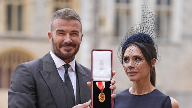 David Beckham präsentiert mit Victoria Beckham einen Orden in rotem Etui.