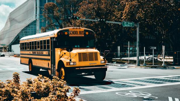 Ein gelber amerikanischer Schulbus fährt durch eine städtische Kreuzung bei Tageslicht.