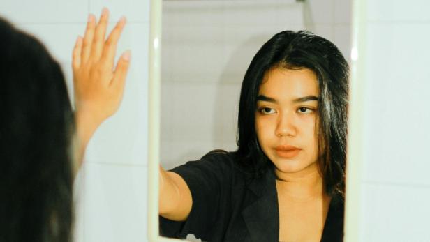 Eine Frau sieht sich im Spiegel an (symbolfoto)