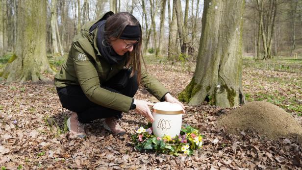 Frau mit Urne und Blumenschmuck im Wald