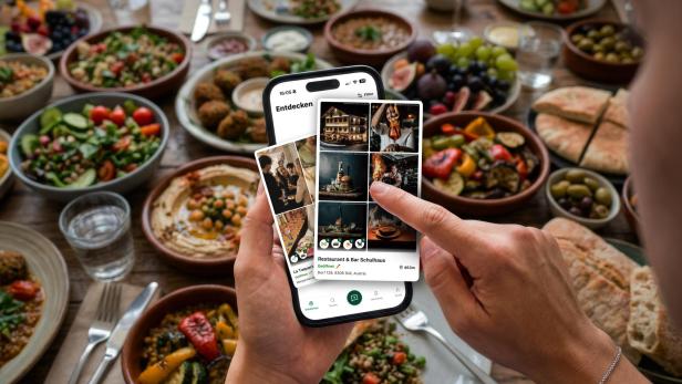 Handy mit Bildern vor mit Essen gefülltem Tisch