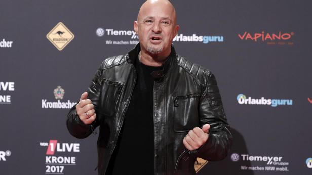Detlef Steves posiert auf dem roten Teppich der 1LIVE Krone 2017 in schwarzer Lederjacke vor Sponsoren-Logos.