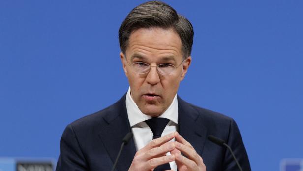 Mark Rutte spricht vor einem blauen Hintergrund und gestikuliert mit den Händen.