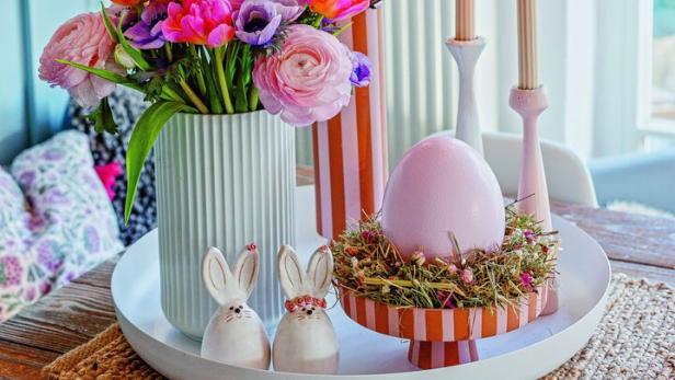 Auf einem Tablett sind ein Strauß Blumen, Deko-Osterhasen und ein Nest mit Straußenei angeordnet
