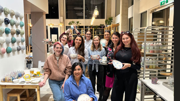 Gruppe von Frauen präsentiert selbst gestaltete Keramik in einem hellen Atelier.