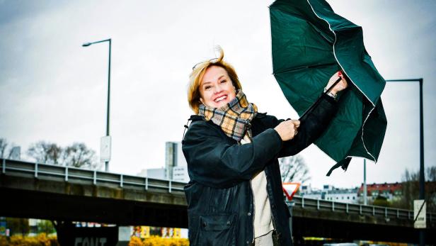 Humorforscherin Doris Bach mit Regenschirm lachend im Wind