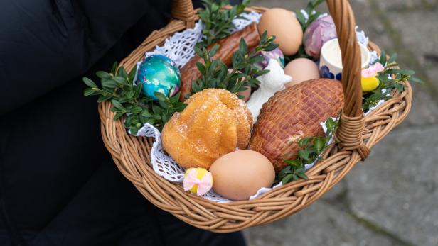 Woman holding traditional woven wicker Easter Paschal basket, filled with food for blessing in a church.