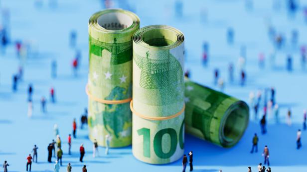 Drei aufgerollte 100-Euro-Scheine stehen zwischen vielen kleinen, verstreut stehenden Menschenfiguren auf blauem Grund.