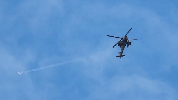A plane flies overhead an Israeli Apache helicopter near the Israeli  of the border with Lebanon, amid escalation between Iran-backed Hezbollah and Israel and the U.S.-Israeli conflict with Iran