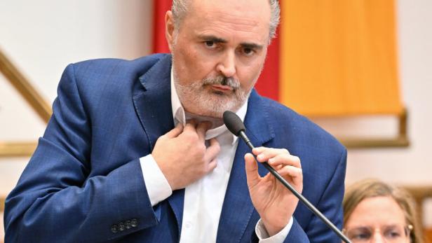 Doskozil im Landtag, während einer Rede hält er sich die Operationsstelle am Hals mit den Fingern zu