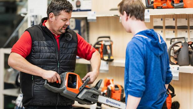 Ein Mann zeigt einem jüngeren Mann eine Schneidemaschine 