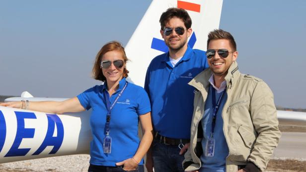 Drei Personen stehen vor einem Segelflugzeug und tragen Sonnenbrillen.