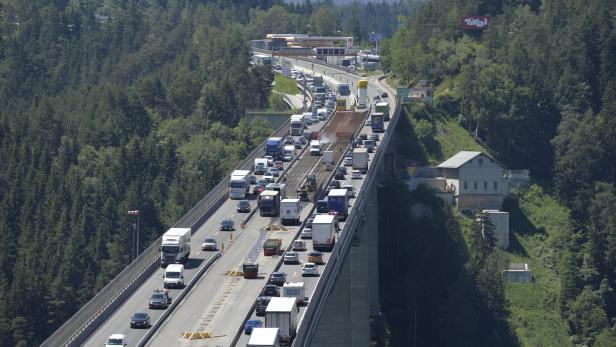 Auf einer hohen Brücke staut sich der Verkehr aus Autos und Lkw, während Bauarbeiten stattfinden.