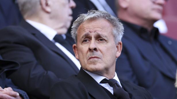 Pierre Littbarski mit grauem Haar und dunklem Anzug schaut aufmerksam zur Seite.