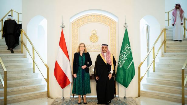 Zwei Personen stehen zwischen der österreichischen und der saudi-arabischen Flagge in einem repräsentativen Gebäude.