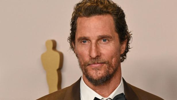 Matthew McConaughey trägt Fliege und braunen Anzug vor hellem Hintergrund.