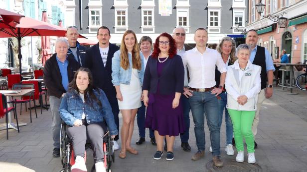 Eine Gruppe von etwa zwölf Personen posiert im Freien vor einem Gebäude.