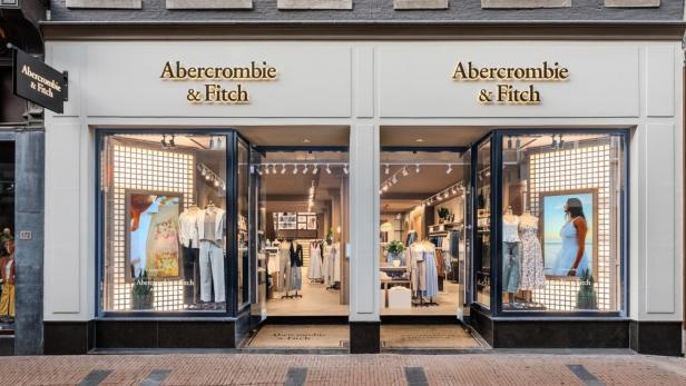 Eingang eines Abercrombie & Fitch Geschäfts mit Schaufensterpuppen in Sommerkleidung und großen Werbepostern.