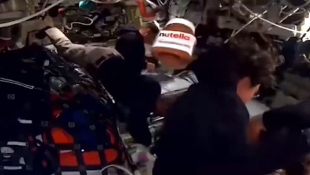 Ein Nutella-Glas schwebt schwerelos zwischen Astronauten in der Raumkapsel.