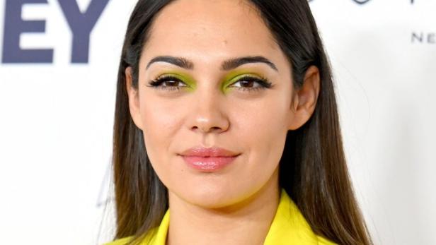 Nilam Farooq mit gelbem Blazer und grünem Lidschatten blickt in die Kamera.