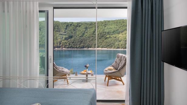 Blick aus einem modernen Schlafzimmer auf eine Terrasse mit Sitzmöbeln und Meerblick in Istrien.
