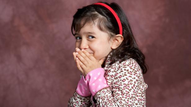 Ein Mädchen kichert und greift sich zum Mund.