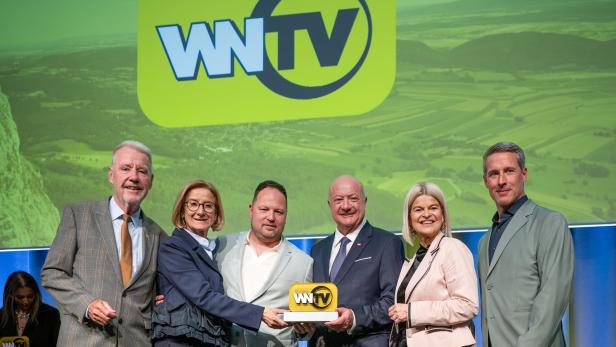 Bürgermeister Klaus Schneeberger, Landeshauptfrau Johanna Mikl-Leitner, Geschäftsführer Bernd Grossmann, Bundeskanzler Christian Stocker, Verteidigungsministerin Klaudia Tanner und Geschäftsführer Erich Lehner stehen vor einem grünen Plakat mit dem Logo von WNTV.