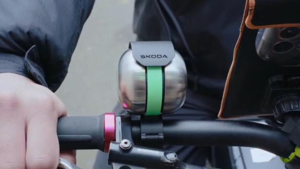 Škoda DuoBell Fahrradklingel mit grünem Band am Lenker eines Fahrrads montiert.
