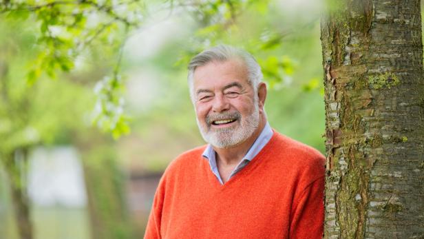 Ein lächelnder Harry Wijnvoord mit Bart lehnt an einem Baum im Grünen.