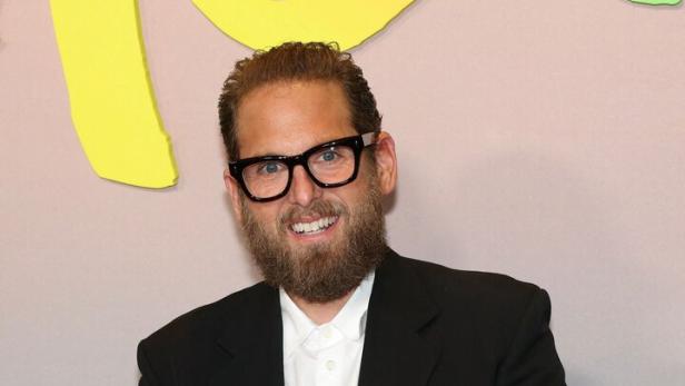 Jonah Hill trägt einen schwarzen Anzug, ein weißes Hemd und eine Brille.