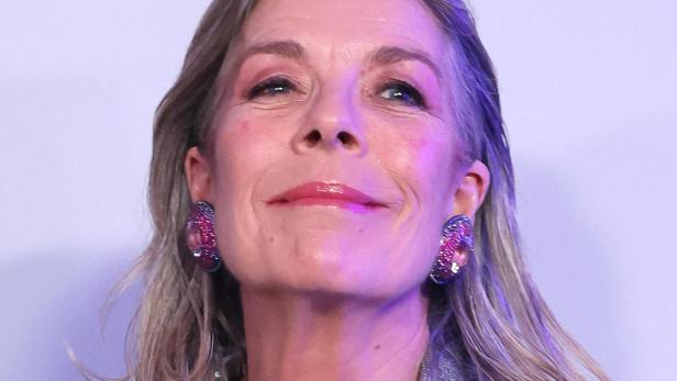 Caroline von Monaco mit blondem Haar trägt einen glitzernden Blazer und auffällige Ohrringe.