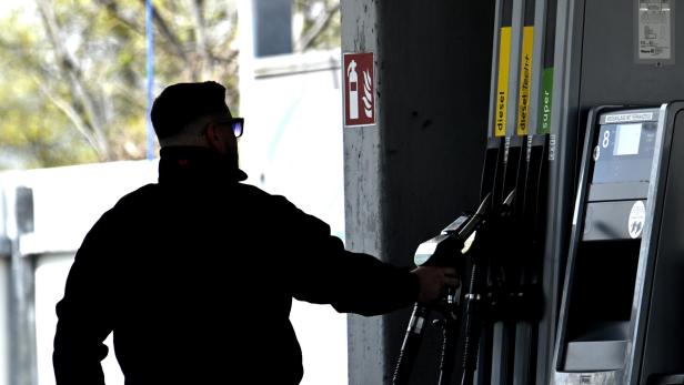 Mann zieht Zapfhahn an einer Tankstelle.