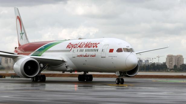 Ein Passagierflugzeug der Royal Air Maroc rollt auf einer nassen Landebahn bei bewölktem Himmel.
