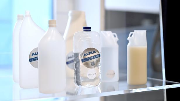 Verschiedene ALPLA-Flaschen, einige mit Flüssigkeit gefüllt, stehen auf einem Regal.