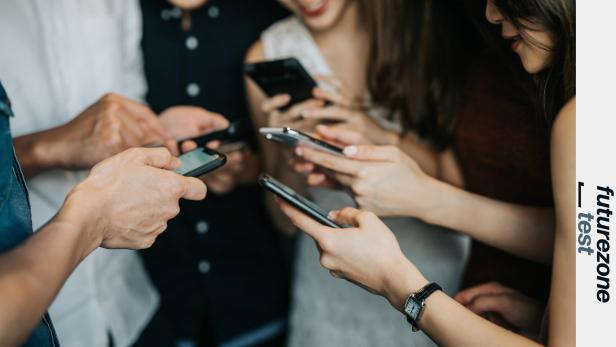 Mehrere Personen halten und benutzen Smartphones in einer Gruppe.