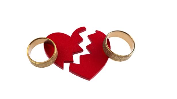 Wedding ring with broken heart on white background