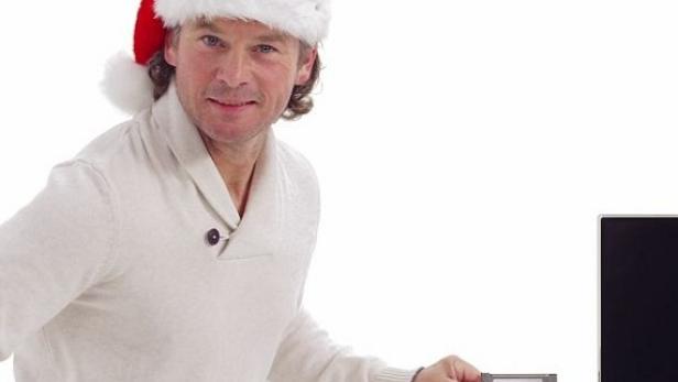 Ein Mann mit Weihnachtsmütze hält eine Speicherkarte vor einen Fernseher.