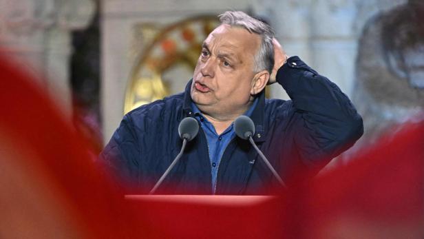 Viktor Orbán steht am Rednerpult und fährt sich nachdenklich durch die Haare.