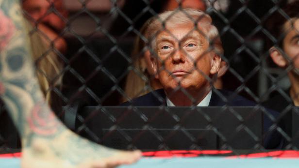 Donald Trump schaut durch einen Käfig auf einen tätowierten Fuß.