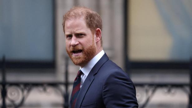 Prinz Harry, mit Bart und Anzug, blickt zur Seite.