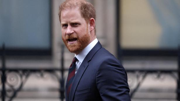 Prinz Harry, mit Bart und Anzug, blickt zur Seite.