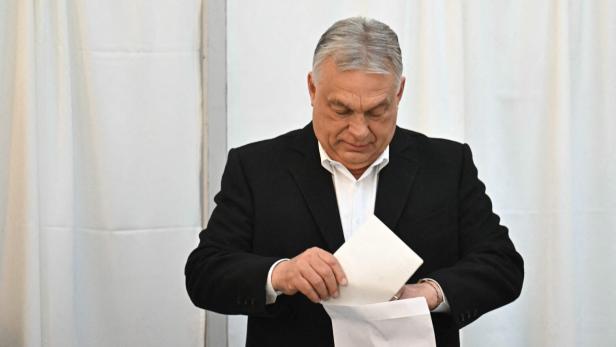 Viktor Orban steckt einen Zettel in einen Umschlag.