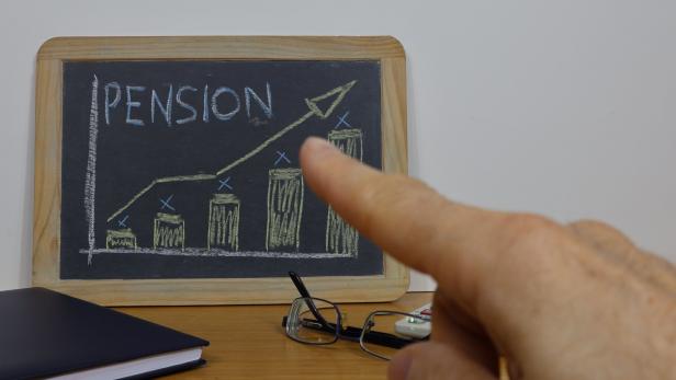 Businessman pointing to a positive graph on a blackboard with the word Pension written on it.