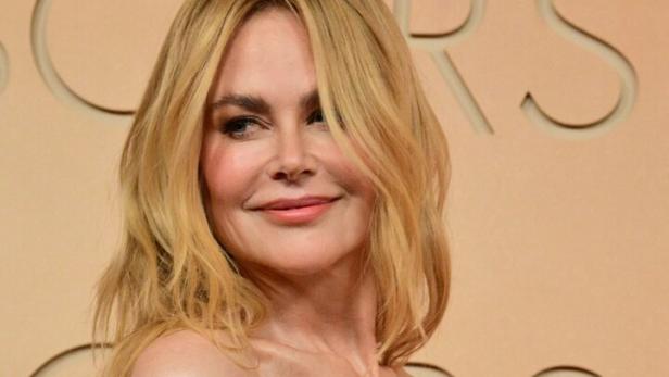 Nicole Kidman in einem trägerlosen, mit Pailletten besetzten Kleid vor einem beigen Hintergrund.