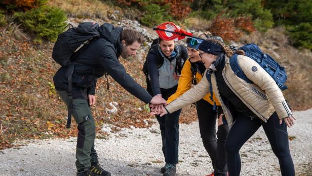Vier Personen mit Rucksäcken begrüßen sich mit einem Handschlag.