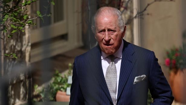 König Charles III. trägt einen gestreiften Anzug und eine Krawatte im Freien.