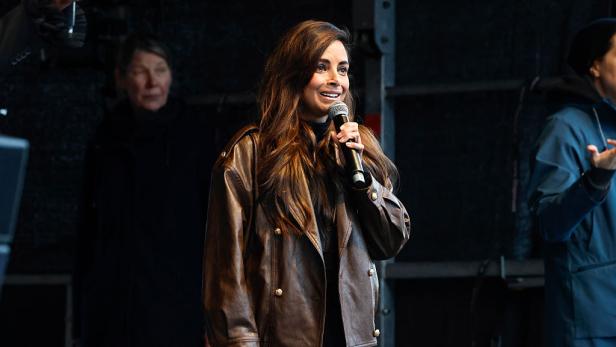 Collien Fernandes spricht mit Mikrofon auf einer Bühne während einer öffentlichen Veranstaltung.