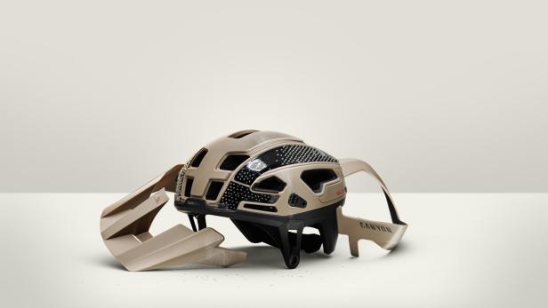 Fahrradhelm mit abgelöster Außenschale und sichtbarer RLS-Technologie auf hellem Hintergrund.