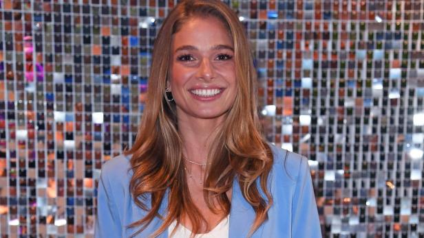 Lola Weippert steht lächelnd vor einer glitzernden Wand, obwohl sie aktuell eine schwere Lebenskrise durchmacht.