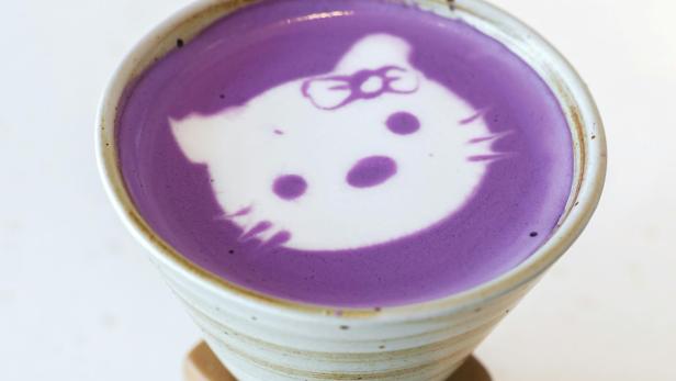 Violettes Milchgetränk mit einem Katzenmotiv im Milchschaum